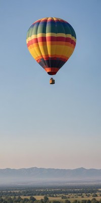 A hot air balloon floats over a valley