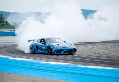 A blue sports car drifts on a racetrack