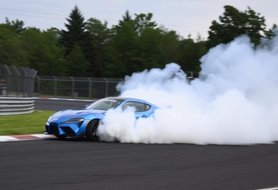 A blue sports car drifts on a racetrack