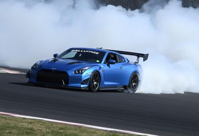 A blue sports car drifts on a racetrack