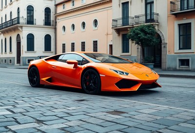 A bright orange sports car is parked on a cobblestone street