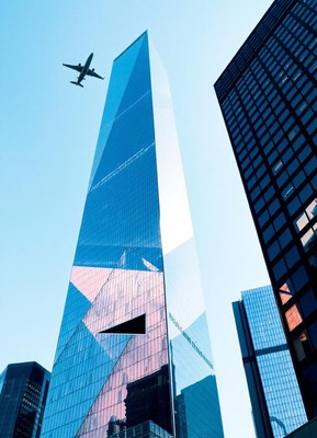 A plane flies over tall skyscrapers in a city