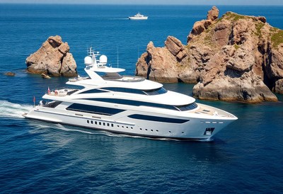 A white yacht sails past rocky islands