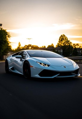 A white sports car drives on a street at sunset