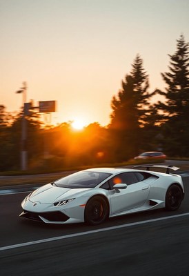 A white sports car drives on a road at sunset