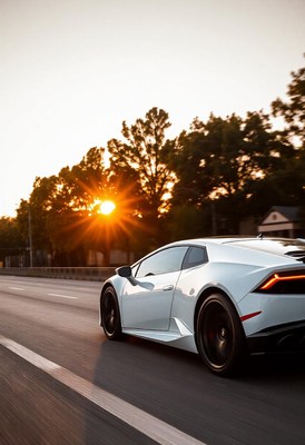 A white sports car drives down a highway at sunset