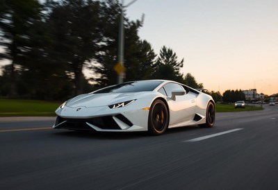 A white sports car drives on a street in the evening