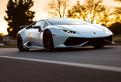 A white sports car drives down a road at sunset
