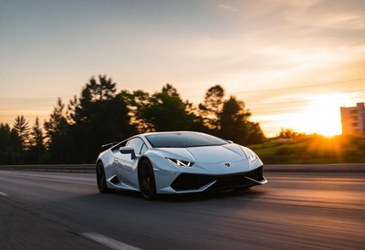 A white sports car drives down a highway at sunset