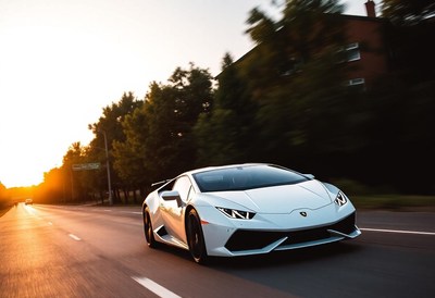 A white sports car drives down a road at sunset