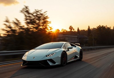 A white sports car drives on a road at sunset