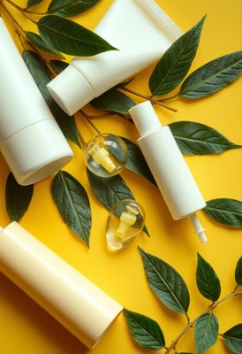 White bottles and green leaves on a yellow background