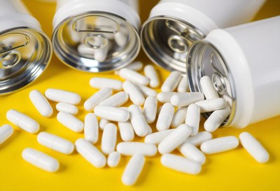 White capsules spill from cans onto a yellow surface
