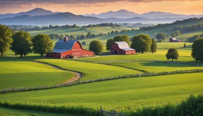 Two red barns sit in a green valley at sunrise