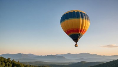 A hot air balloon floats over the mountains at sunrise