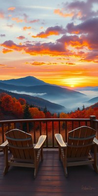 Two chairs sit on a deck overlooking a mountain sunset
