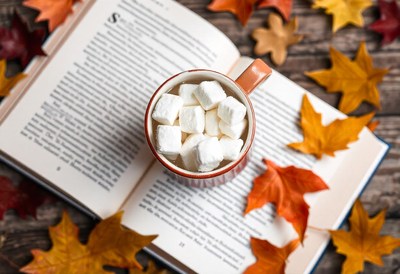 Hot chocolate with marshmallows on a book, autumn leaves