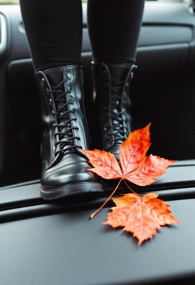 Black boots and autumn leaves rest on a car dashboard