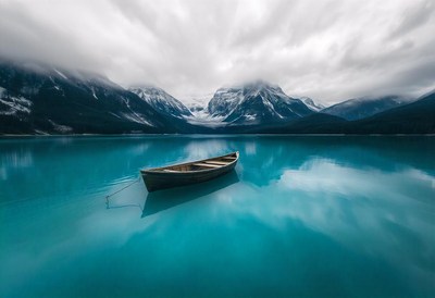 A small boat sits on a calm lake in the mountains