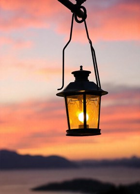 A lantern hangs against a sunset over the water