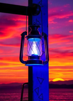 A lantern glows blue against a vibrant sunset