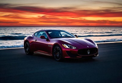 A red sports car parked on the beach at sunset