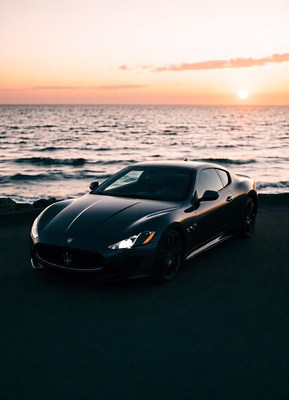 A black sports car parked near the ocean at sunset