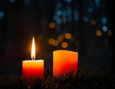 Two candles burn brightly on a wreath