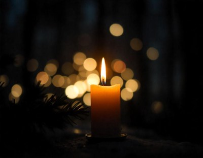 A candle shines amid bokeh lights