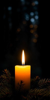 A single candle burns brightly in the dark