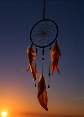 A dreamcatcher hangs in the sunset sky
