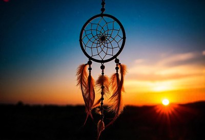 A dreamcatcher hangs against a vibrant sunset
