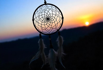 A dream catcher hangs against a sunset