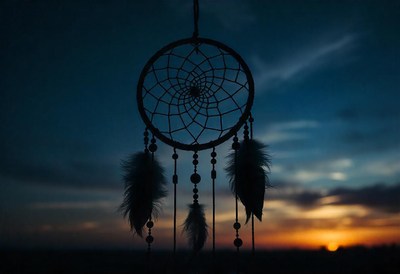 A dream catcher hangs against a vibrant sunset