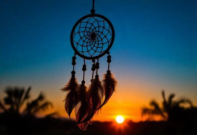 A dreamcatcher hangs against a vibrant sunset