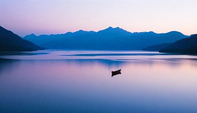 A boat rests on a tranquil lake at sunset