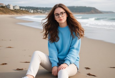 A young woman sits on a sandy beach