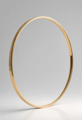 A gold bangle lies on a plain surface