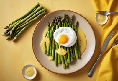 A plate of asparagus with a fried egg and hollandaise sauce