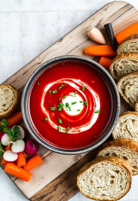 A bowl of red soup with a dollop of cream and parsley on top