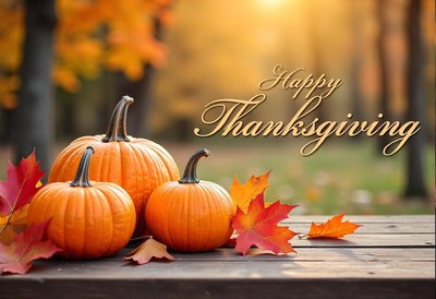 Three pumpkins sit on a wooden table with fall leaves
