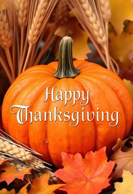 Thanksgiving pumpkin amid wheat and leaves