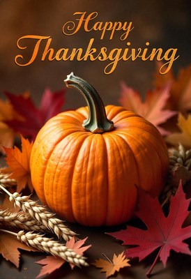 A pumpkin sits among fall leaves and wheat stalks