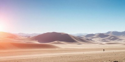 A solitary figure strides through the desert sky