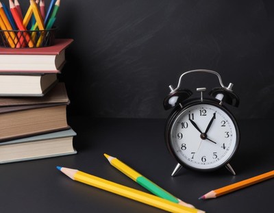 Alarm clock, pencils, and books on a desk