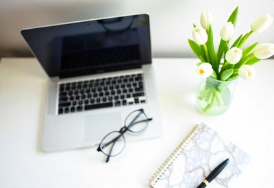 Desk with laptop, glasses, notebook, and tulips