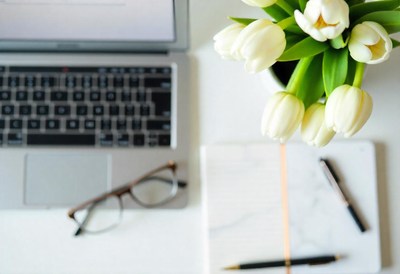 Laptop, glasses, and notebook with tulips on desk