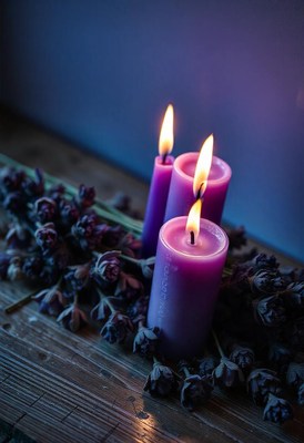Three purple candles are lit and set on a wooden surface