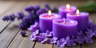 Purple candles glow on a wooden surface with lavender
