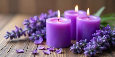 Three purple candles with lavender on a wooden table